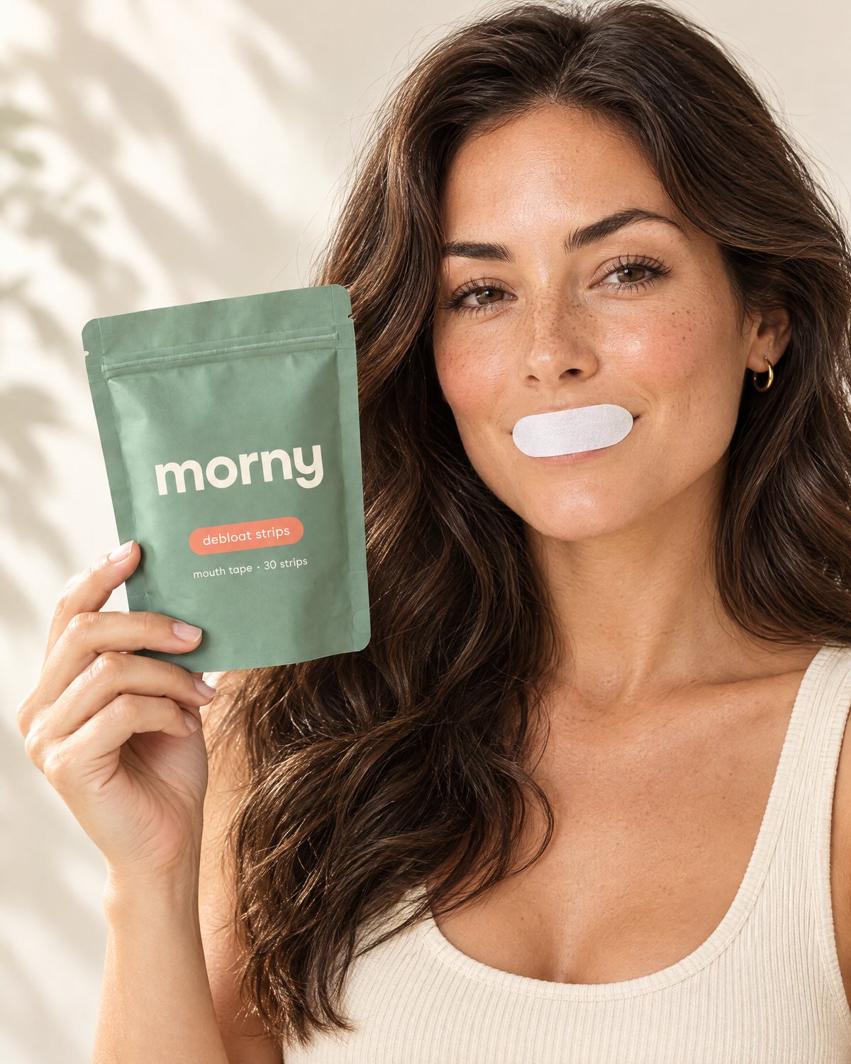 A woman wearing a morny strip, holding the morny pouch beside her face